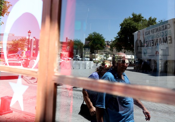 epa06827004 People walk in front of the huge picture of Turkish President Recep Tayyip Erdogan in Gaziantep, Turkey, 21 June 2018. Turkish President Erdogan announced on 18 April 2018 that Turkey will ...
