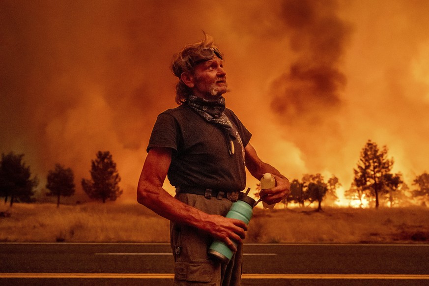Grant Douglas pauses to drink water while evacuating as the Park Fire jumps Highway 36 near Paynes Creek in Tehama County, Calif., on Friday, July 26, 2024. (AP Photo/Noah Berger)
