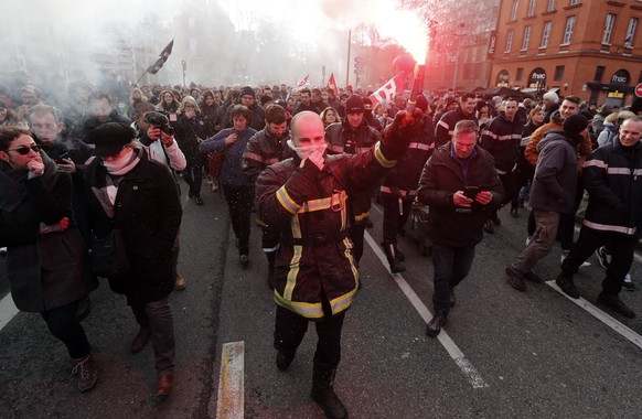 epa10415128 A firefighter lights a red torch during a national strike led by French trade unions against the government's pension reform, in Toulouse, January 19, 2023. The French government...