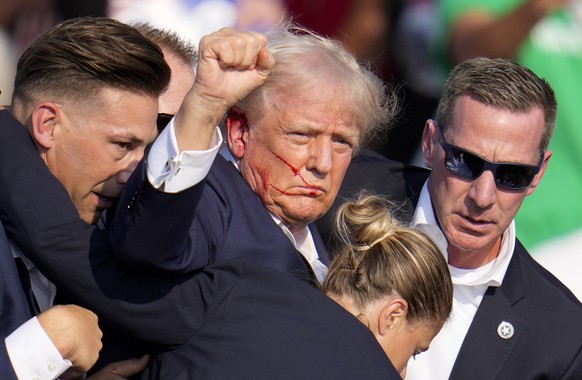 Republican presidential candidate former President Donald Trump is helped off the stage by U.S. Secret Service agents at a campaign event in Butler, Pa., on Saturday, July 13, 2024. (AP Photo/Gene J.  ...