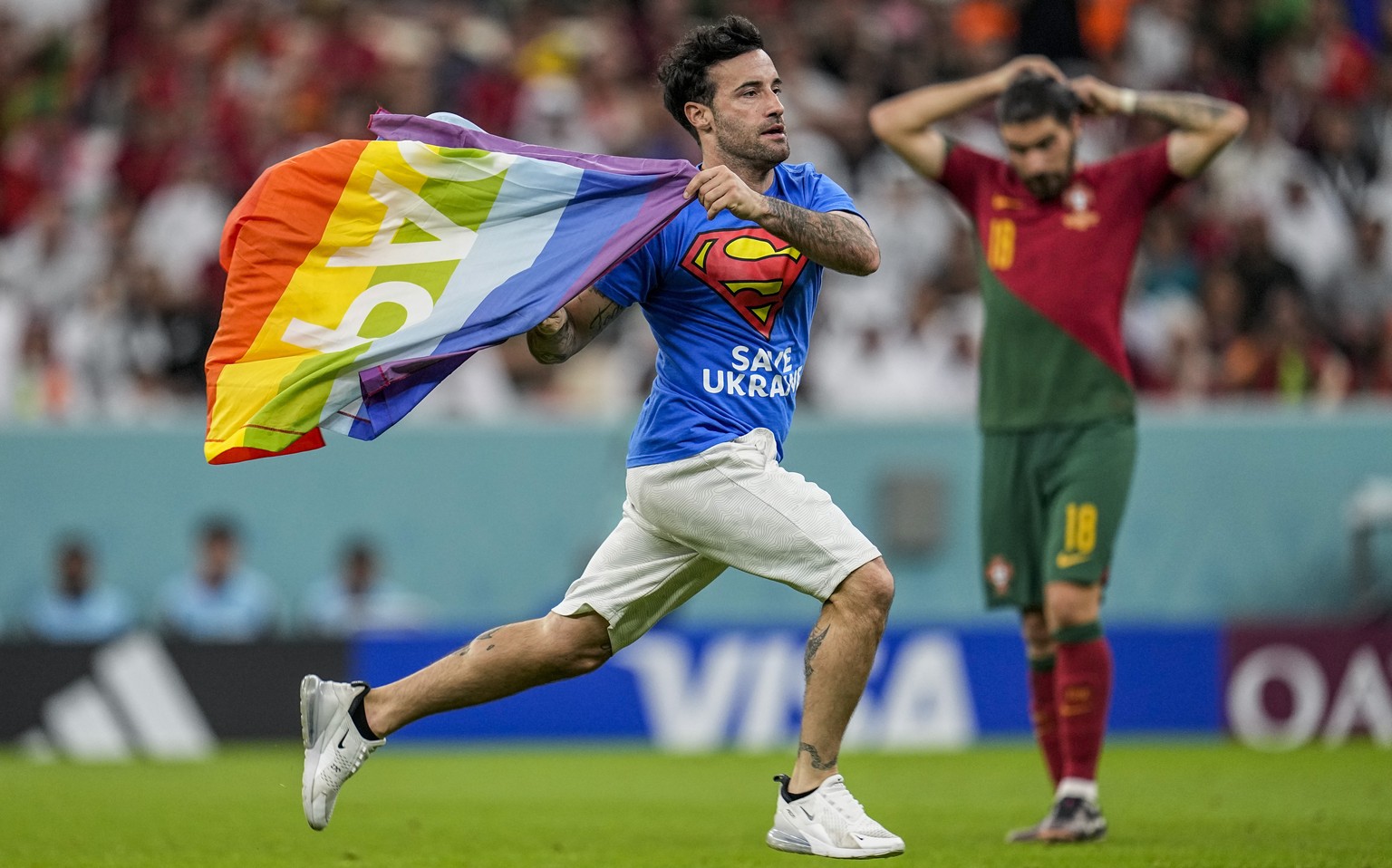 A pitch invader runs across the field with a rainbow flag during the World Cup group H soccer match between Portugal and Uruguay, at the Lusail Stadium in Lusail, Qatar, Monday, Nov. 28, 2022. (AP Pho ...