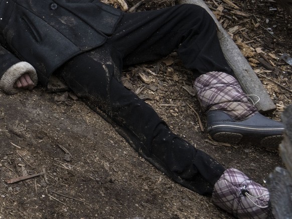 A woman stands next to three people killed in the courtyard of a house in Bucha, on the outskirts of Kyiv, Ukraine, Tuesday, April 5, 2022. (AP Photo/Rodrigo Abd)