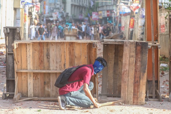 epa11481768 A protester takes cover as quota protesters clash with Bangladesh Chhatra League (BCL) activists in Dhaka, Bangladesh, 16 July 2024. Police report at least six people were killed and dozen ...