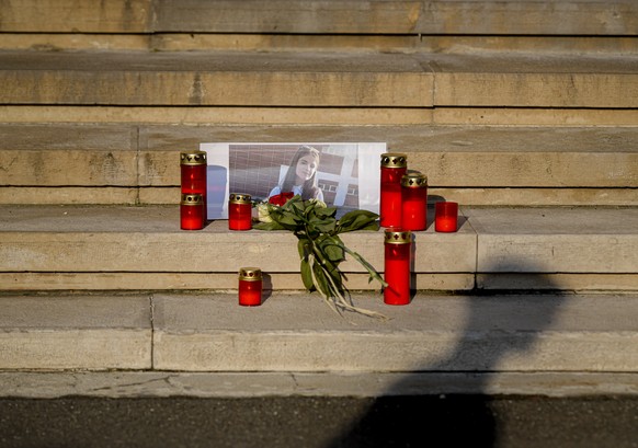 A man casts a shadow outside the Interior Ministry, in Bucharest, Romania, Friday, July 26, 2019, next to flowers and candles placed in memory of a 15 year-old girl, killed after after police took 19  ...