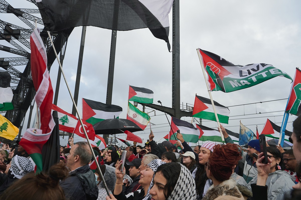 epa12281381 Protesters wave flags as they walk across the Sydney Harbour Bridge during the Palestine Action Group's "March for Humanity", a pro-Palestinian march, in Sydney, Australia,  ...