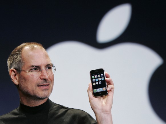 FILE- In this Jan. 9, 2007, file photo, Apple CEO Steve Jobs holds up an iPhone at the MacWorld Conference in San Francisco. Jobs introduced the first iPhone a decade ago. Jobs' &quot;magical product& ...