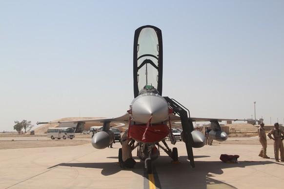Iraqi pilots stand next to one of four new U.S.- made F-16 fighter jets upon their arrival to Balad air base, 75 kilometers (45 miles) north of Baghdad, Iraq, Monday, July 13, 2015. (AP Photo)