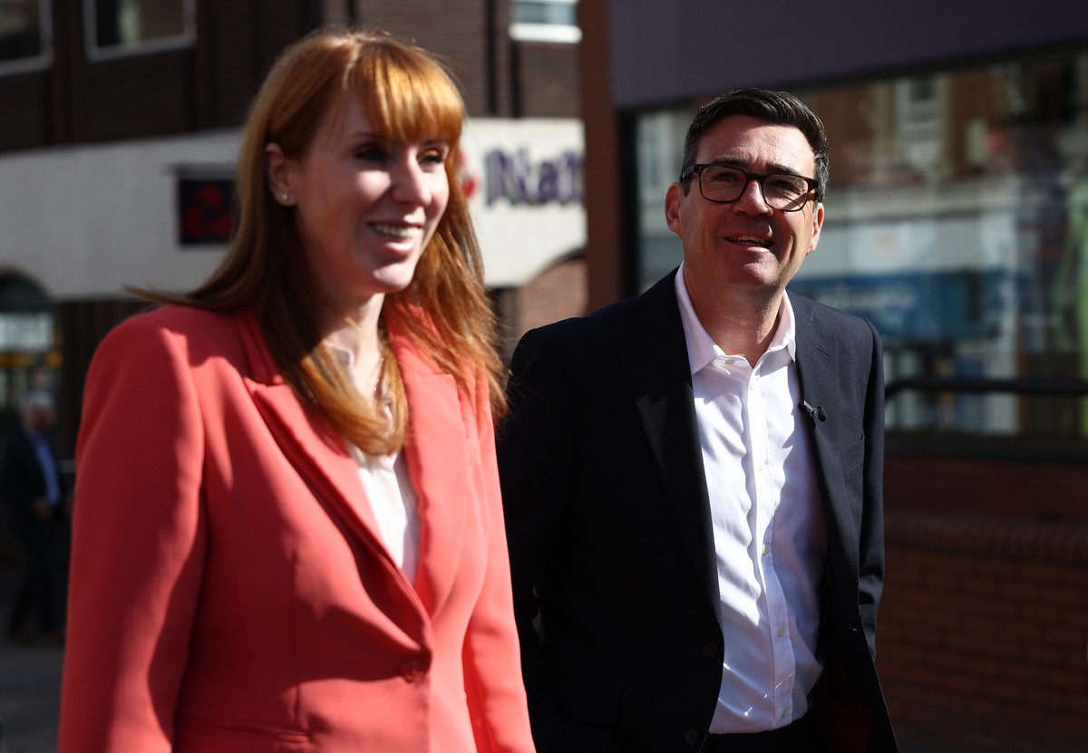 Britain's Prime Minister Andy Burnham, right, and Britain's Housing Secretary Angela Rayner react as they walk past shops during a visit to Ilkeston, Derbyshire, England, Tuesday, Aug. 11, 2 ...