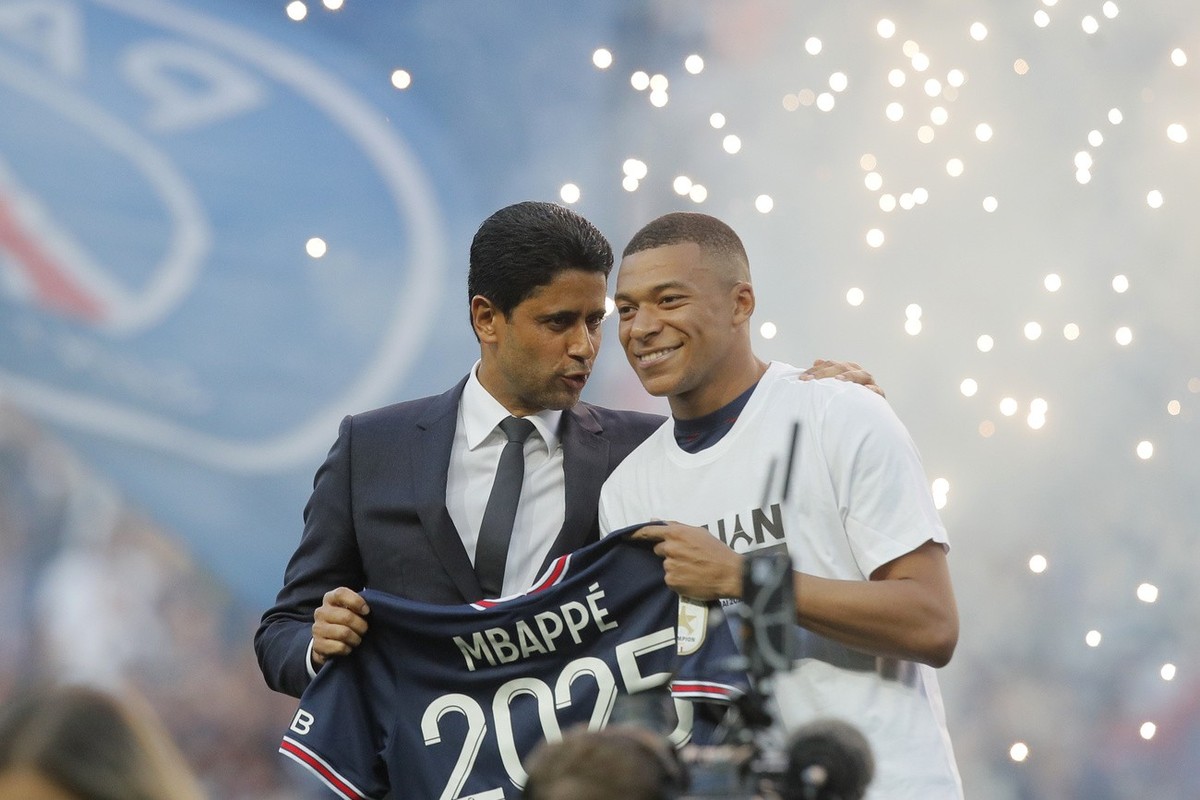 PSG President Nasser Al-Khelaifi, left speaks to PSG's Kylian Mbappe who holds a shirt with his name and 2025 on it as it is announced he has signed a three year extension to his contract on the  ...