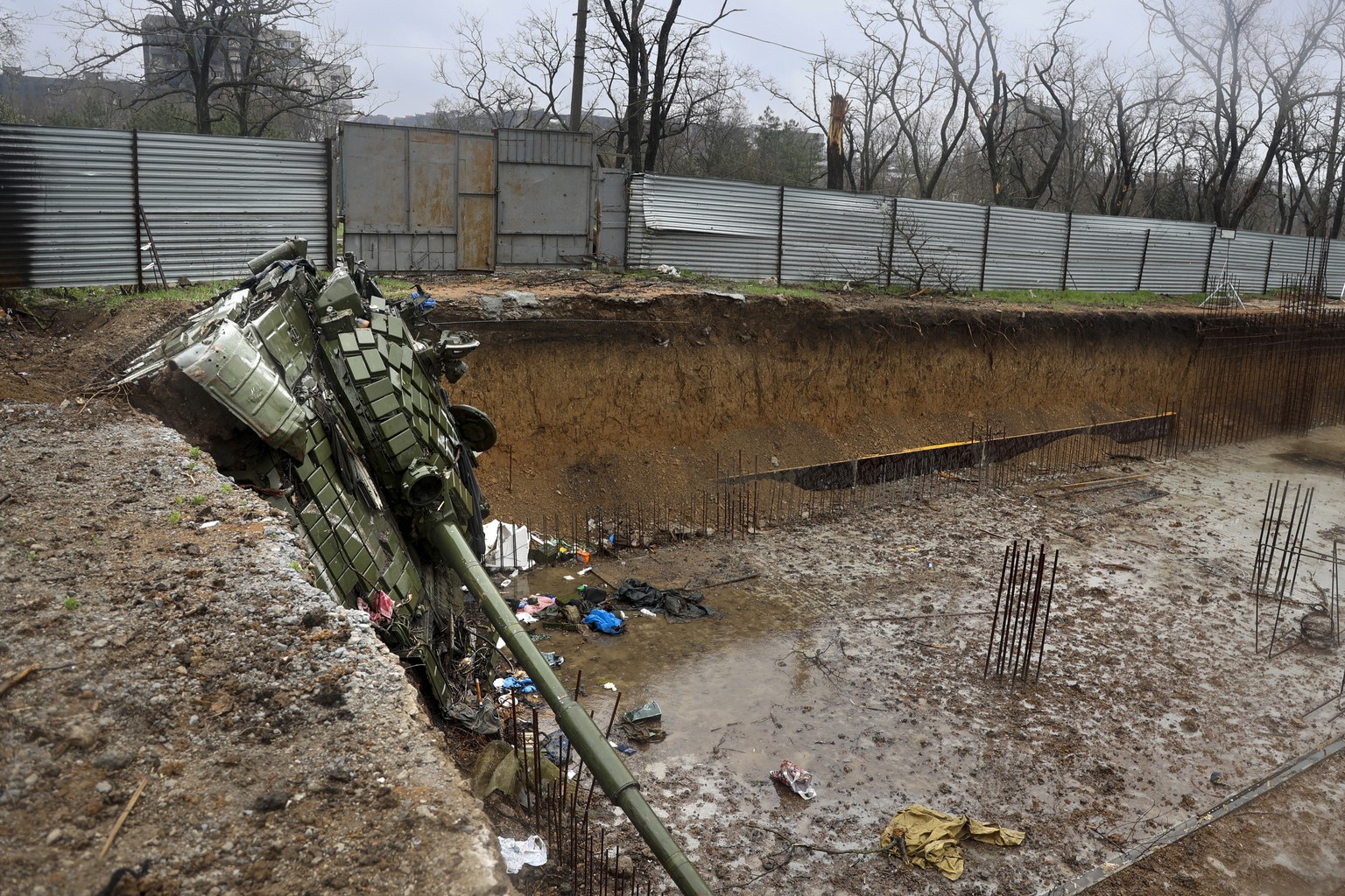 A tank damaged during fighting is seen at the foundation pit for a house under construction in an area that Russian-backed separatists claim to control in the Ukraine city of Mariupol, Wednesday, Apri ...