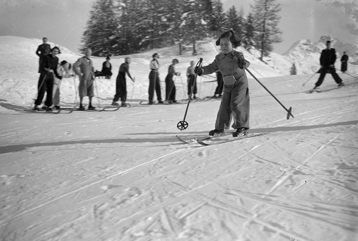 Finding her feet-with difficulty. A very young skier, incorrect attire and wearing a specially small pair of skis, grimly set her lips, but shut her eyes as she set out on her first skiing lesson over ...