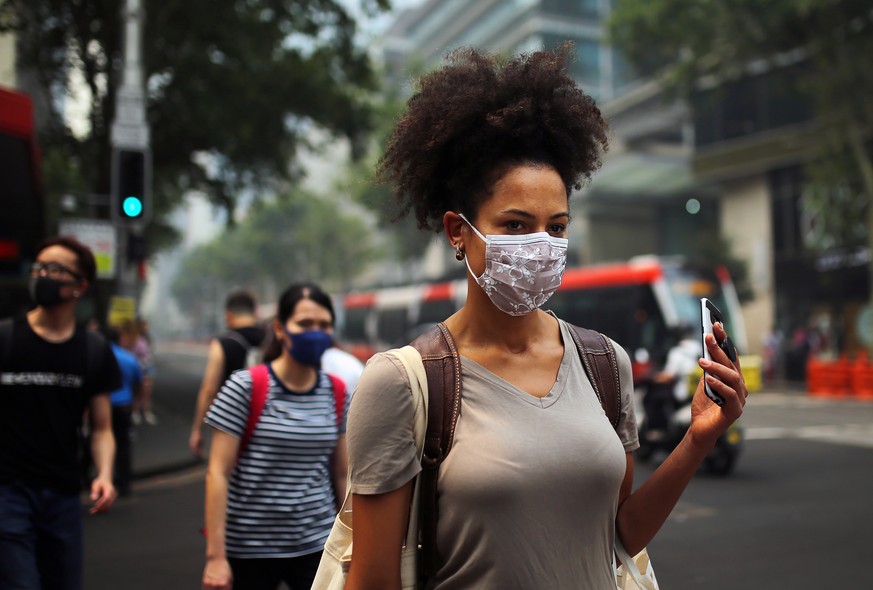 epa08058697 Pedestrians wear masks as smoke and haze from bushfires in New South Wales blankets the CBD in Sydney, Australia, 10 December 2019. The New South Wales environment department says visibili ...