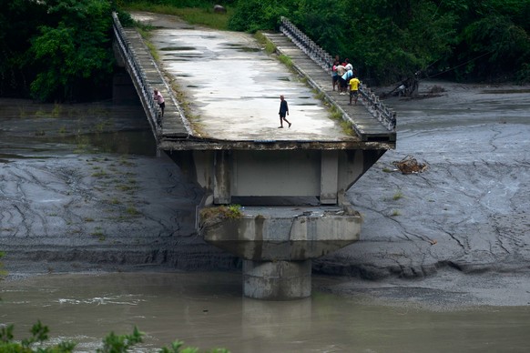 People stand on remnants of a bridge which spanned across Trishuli river and was washed away in flash floods, in Dhading District, Nepal, Sunday, Aug. 30, 2026. (AP Photo/Niranjan Shrestha)
APTOPIX Ne ...