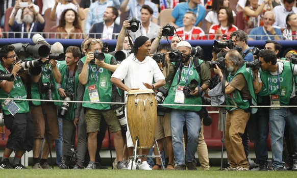 Former Brazilian soccer player Ronaldinho, centre, surrounded by photographers plays on the drums as he takes part in the closing ceremony before the start of the the final match between France and Cr ...