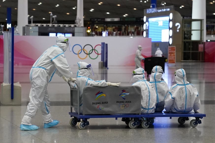 Volunteers ride on a cart at Beijing-Capital International Airport after the conclusion of the 2022 Winter Olympics, Sunday, Feb. 20, 2022, in Beijing. (AP Photo/Ashley Landis)