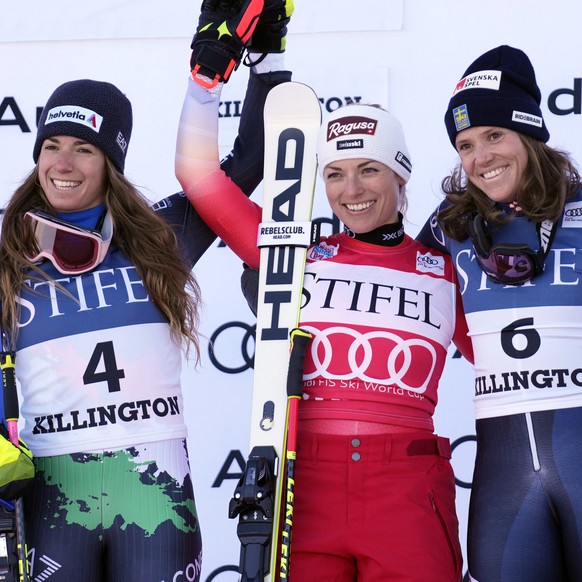 Switzerland's Lara Gut-Behrami, first place, center, and Italy's Marta Bassino, second place, left, and Sweden's Sara Hector, third place, acknowledge applause on the podium following a World Cup gian ...