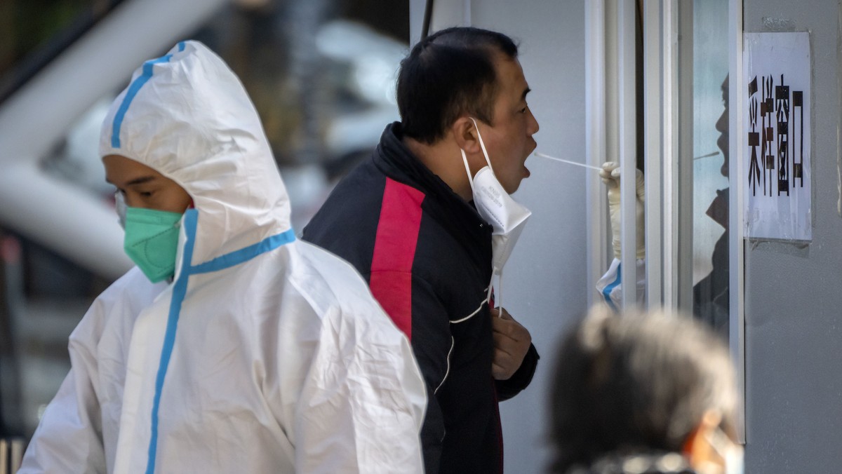 A man has his throat swabbed for a COVID-19 test at a coronavirus testing site in Beijing, Tuesday, Nov. 1, 2022. Shanghai Disneyland was closed and visitors temporarily kept in the park for virus tes ...