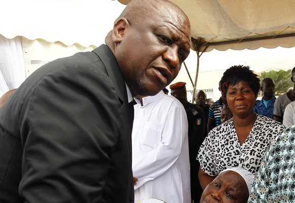 epa09066451 (FILE) - Ivorian minister of security and interior Hamed Bakayoko (L) comforts parents of victims who lost lives in the Grand Bassam beach attack during a ceremony to honour the victims in ...