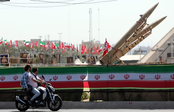 epa13141734 Motorcyclists drive past Iranian missiles 'Zolfaghar' on display above a banner depicting US President Trump at Azadi Square in Tehran, Iran, 30 July 2026. The US completed a   ...