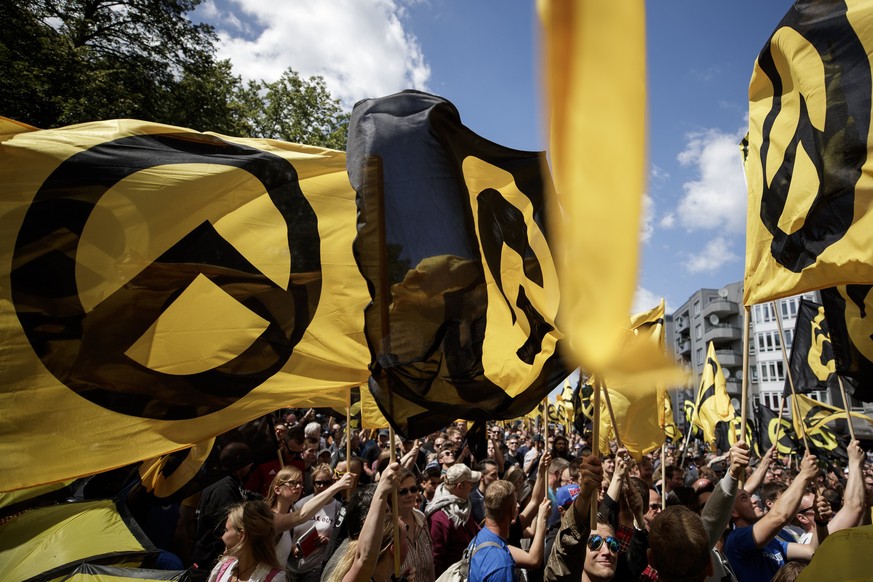 epa06033172 Supporters and members of the Identitarian Movement (Identitaere Bewegung) wave flags as they demonstrate in Berlin, Germany, 17 June 2017. The protesters demand a reduction in mass migrat ...