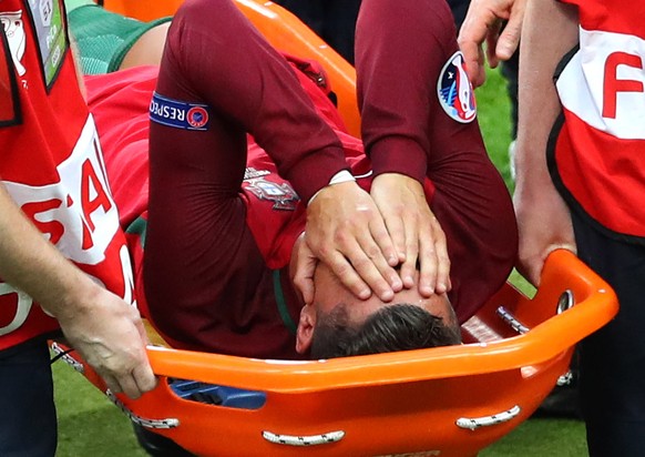 Portugal&#039;s Cristiano Ronaldo covers his face as he is stretchered off the pitch after suffering an injury during the Euro 2016 final soccer match between Portugal and France at the Stade de Franc ...