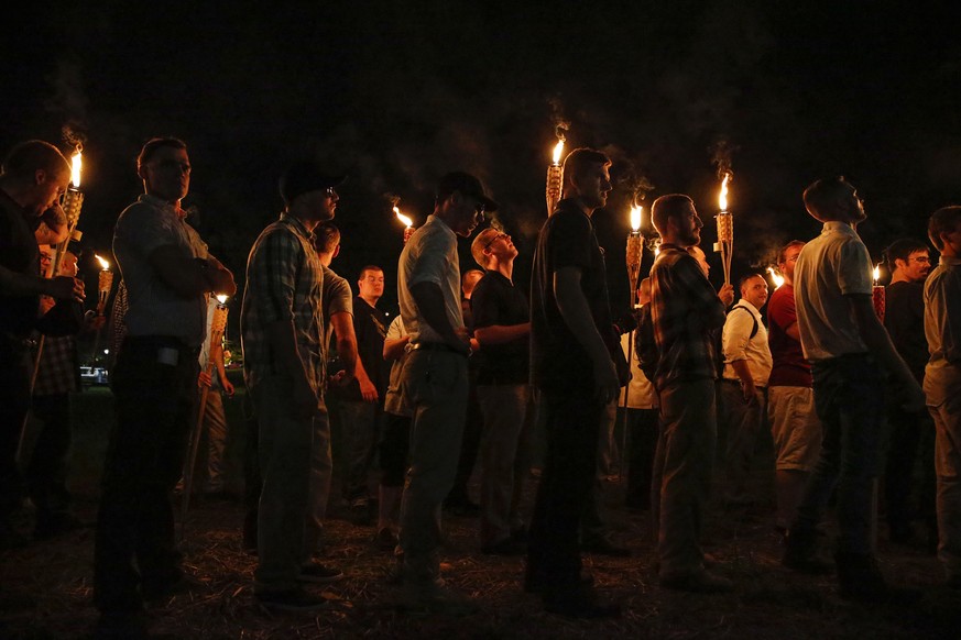 In this photo taken Friday, Aug. 11, 2017, multiple white nationalist groups march with torches through the UVA campus in Charlottesville, Va. Hundreds of people chanted, threw punches, hurled water b ...