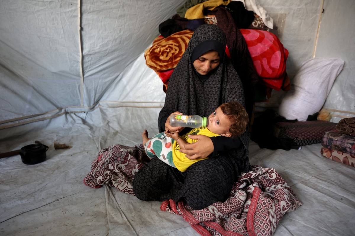 Khadija Sobh, 18 ans, donne à boire à sa fille Janin Sobh, âgée de sept mois, dans leur tente du quartier de Daraj, à Gaza.