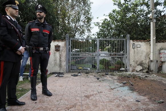 Parts of a car are seen on the ground as Carabinieri military police stand outside the home of investigative journalist Sigfrido Ranucci after an explosive device detonated under the car, in Pomezia,  ...