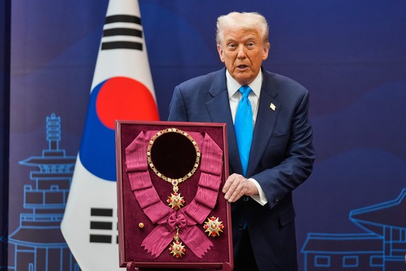 President Donald Trump reacts as he receives an award of the Grand Order of Mugunghwa from South Korean President Lee Jae Myung during a high honor ceremony at the Gyeongju National Museum in Gyeongju ...