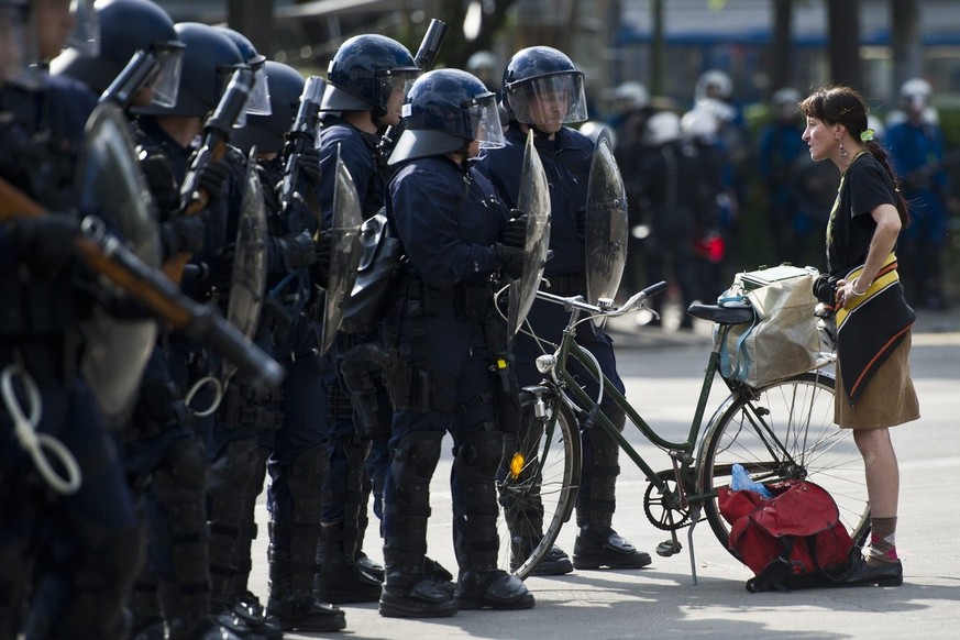 A woman stands next to riot police officers after a labour day demonstration in Zurich, Switzerland, Sunday, on May 1, 2011. (KEYSTONE/Ennio Leanza)..