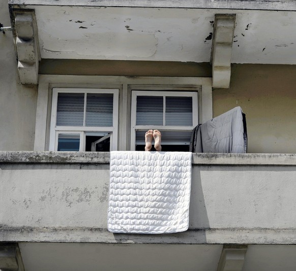 Eine Person geniesst den Sonntag auf einem Balkon in Zuerich, aufgenommen am 3. August 2014. (KEYSTONE/Walter Bieri)
