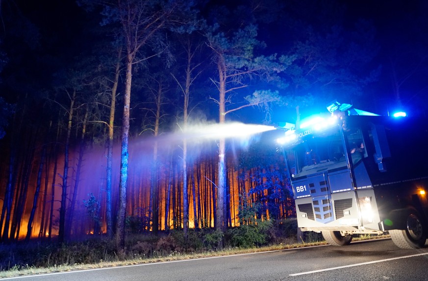 epa06967509 A police water cannon in action during a forest fire in Karlsdorf near Treuenbrietzen in South Brandenburg, Germany, 23 August 2018. Due to a forest fire three villages in Brandenburg, Fro ...