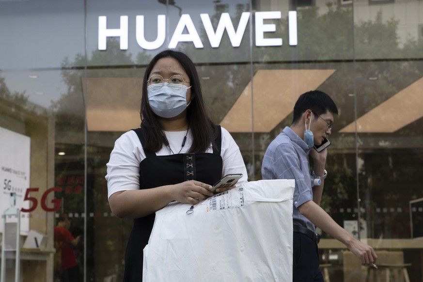 Residents wearing masks to curb the spread of the coronavirus past by a Huawei shop in Beijing on Friday, June 5, 2020. China on Wednesday demanded Washington stop &quot;oppressing Chinese companies&q ...