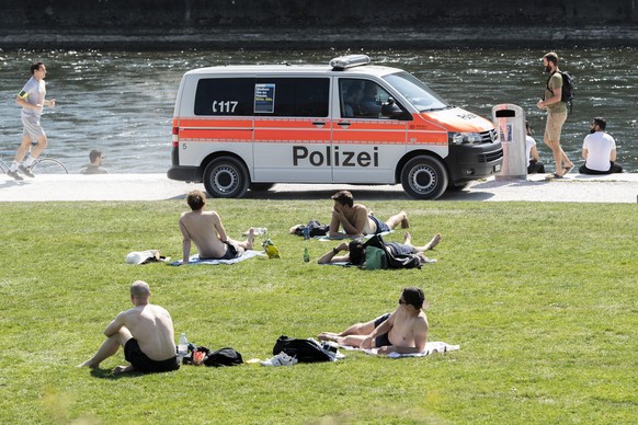 Polizisten in einem Fahrzeug kontrollieren die Menschen an der Limmat auf dem Wipkingerpark, aufgenommen am Samstag, 11. April 2020 in Zuerich. KEYSTONE/Ennio Leanza)