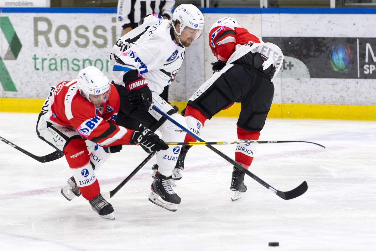 L?attaquant fribourgeois Lukas Lhotak, centre, lutte pour le puck avec l'attaquant valaisan Joachim Vodoz, gauche, et le defenseur valaisan Sami El Assaoui, droite, lors du premier tour de Coupe  ...