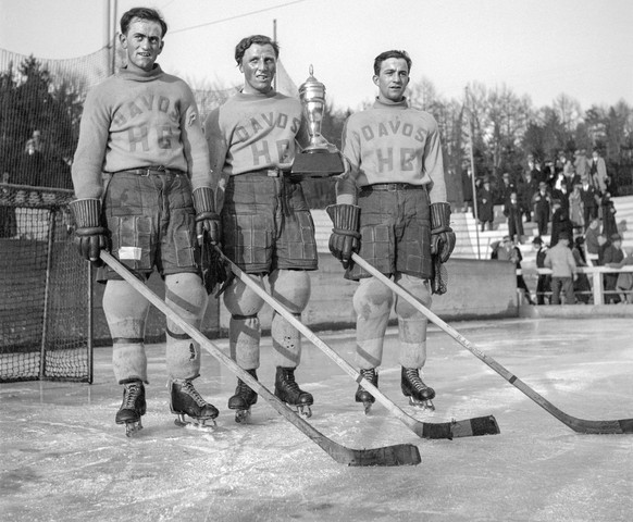 The players of the legendary &quot;ni&quot; forward line of &quot;HC Davos&quot; - Hans Cattini, Bibi Torriani, Pic Cattini (from left to right) - pose with the cup after winning the first Swiss champ ...