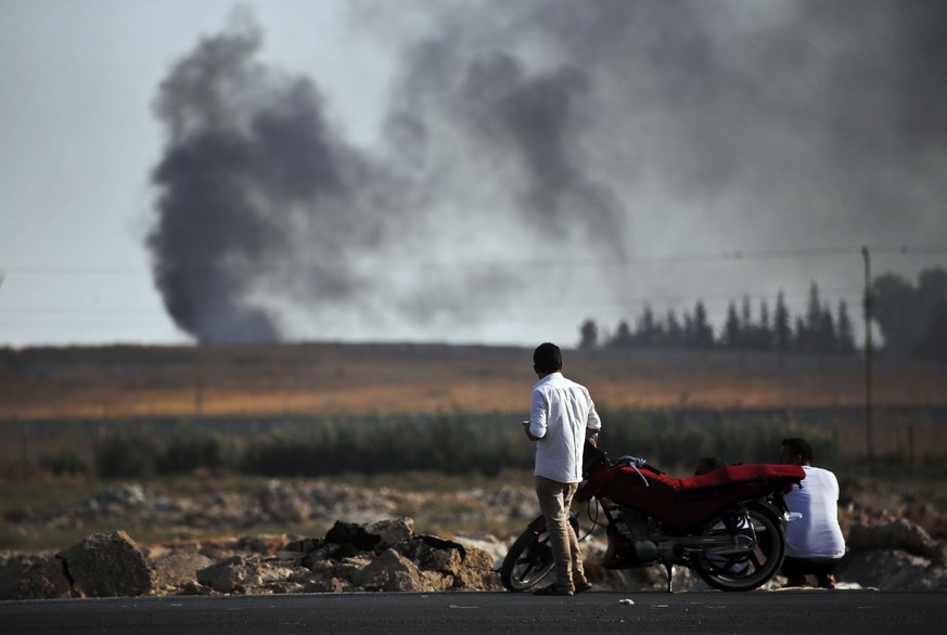People in Akcakale, Sanliurfa province, southeastern Turkey, at the border with Syria, watch smoke billowing from targets inside Syria, during bombardment by Turkish forces, Thursday, Oct. 10, 2019. T ...
