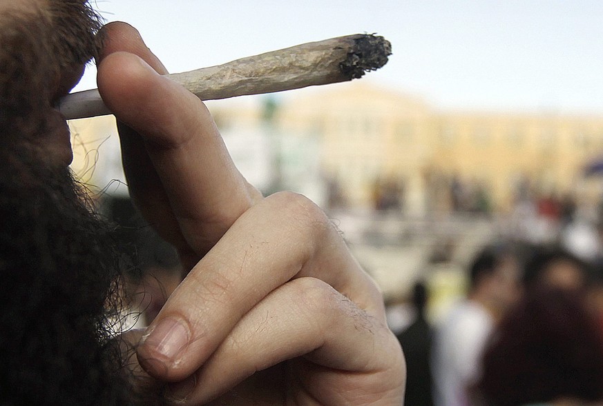 epa04740542 A young man smokes a cannabis cigarette during the 1st Cannabis Festival in Athen&#039;s central Syntagma square, Greece, 09 May 2015. The Cannabis Festival, according to organizers, is a  ...