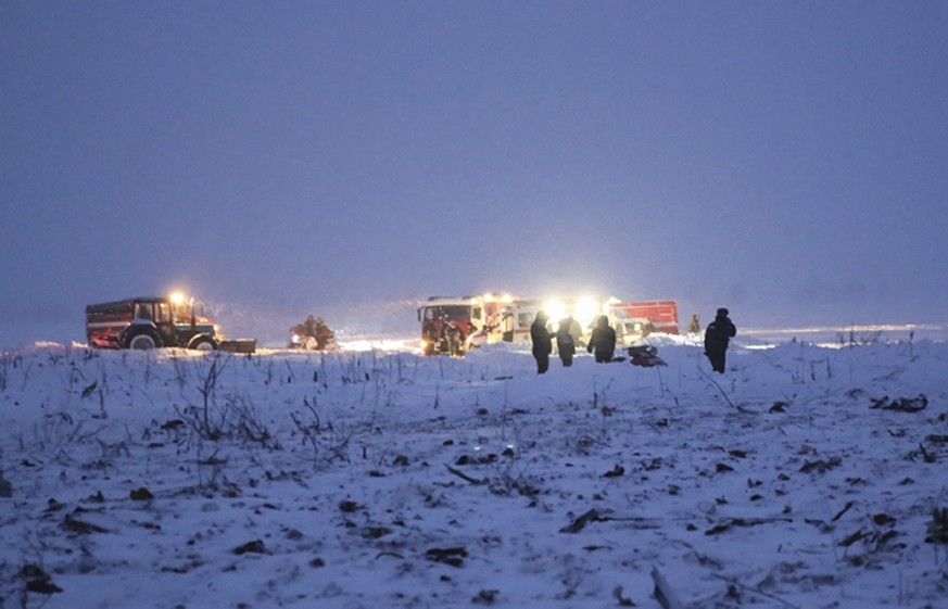 In this photo provided by the Russian Emergency Situations Ministry, Russian Ministry for Emergency Situations employees work at the scene of a AN-148 plane crash in Stepanovskoye village, about 40 ki ...