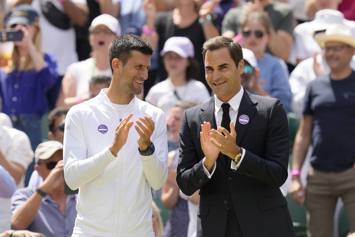 Serbia's Novak Djokovic and Switzerland's Roger Federer applaud during a 100 years of Centre Court celebration on day seven of the Wimbledon tennis championships in London, Sunday, July 3, 2 ...