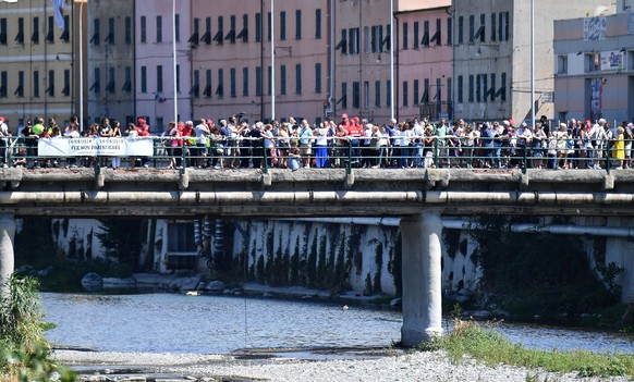 epa07772983 Some 43 roses are tossed into the Polcevera River by citizens of displaced committees during an alternative memorial ceremony for the victims on the first anniversary of the Morandi highwa ...