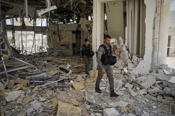 Israeli border police officers walk at the entrance of a residential building hit by a missile launched from Iran, in Petah Tikva, Israel, Monday, June 16, 2025. (AP Photo/Baz Ratner)
Israel Iran Mide ...