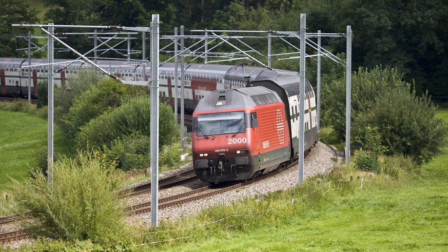 An InterCity train with IC2000 double-storeyed coaches and a Re 460 locomotive of Swiss Federal Railways SBB drives through a curve in the vicinity of Flawil in the canton of St. Gallen, Switzerland,  ...