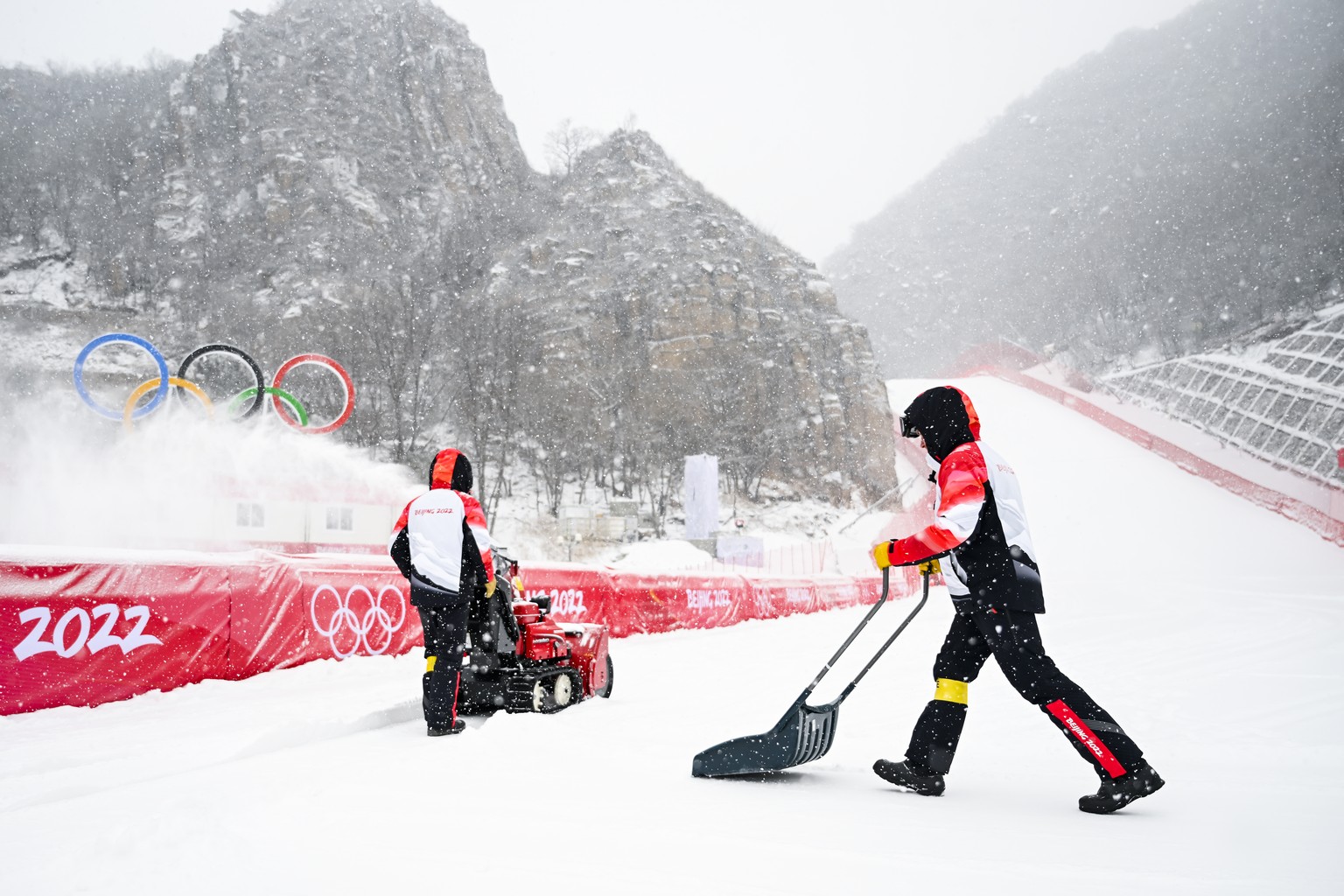 Volunteer removes fresh snow in the finish area of the Alpine Skiing place at the 2022 Olympic Winter Games in Yanqing, China, on Sunday, February 13, 2022. (KEYSTONE/Jean-Christophe Bott)