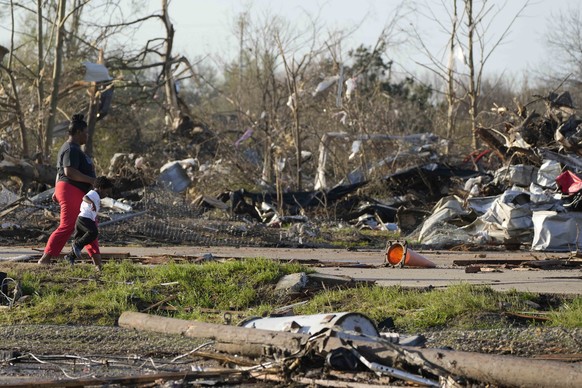 A pair of residents walk through the remains of their tornado demolished mobile home park, looking through the piles of debris, insulation, and home furnishings to see if anything is salvageable in Ro ...