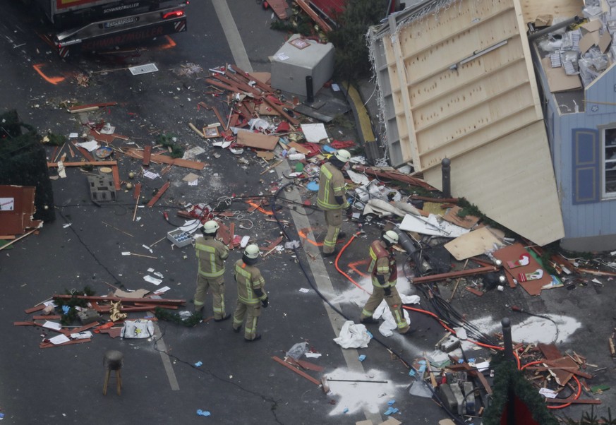 FILE - In this Dec. 20, 2016 file photo, German firefighters look at the debris after a truck attack on a Christmas market in Berlin that left 12 dead. In Britain, a man drove a car into pedestrians i ...