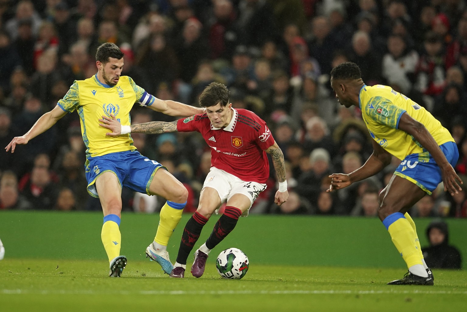 Manchester United&#039;s Alejandro Garnacho, centre, is challenged by Nottingham Forest&#039;s Willy Boly, right, and Remo Freuler during the English League Cup semifinal second leg soccer match betwe ...