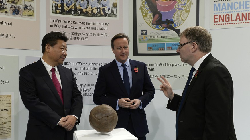 Britain&#039;s Prime Minister David Cameron (C) and China&#039;s President Xi Jinping (L) view the football used in the first World Cup final during a visit to the City Football Academy in Manchester, ...