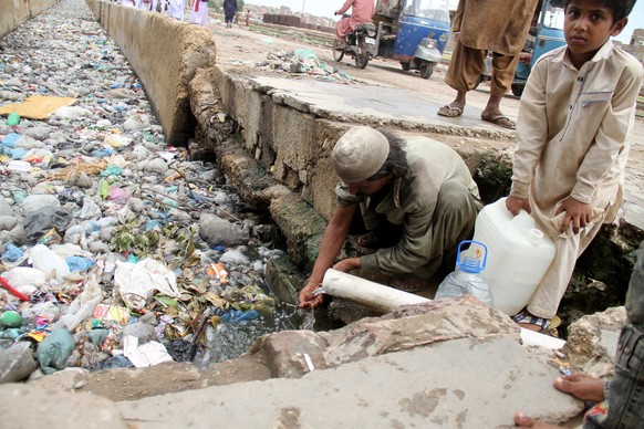 epa06160200 People collect drinking water from a water pipe over a sewage line in Hyderabad, Pakistan, 24 August 2017. Swiss Federal Institute of Aquatic Science and Technology, published a research o ...