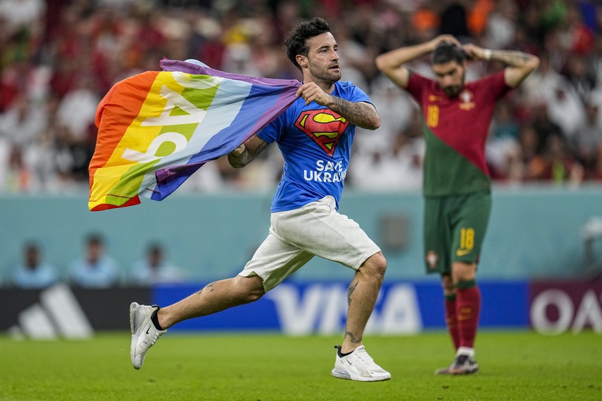 A pitch invader runs across the field with a rainbow flag during the World Cup group H soccer match between Portugal and Uruguay, at the Lusail Stadium in Lusail, Qatar, Monday, Nov. 28, 2022. (AP Pho ...